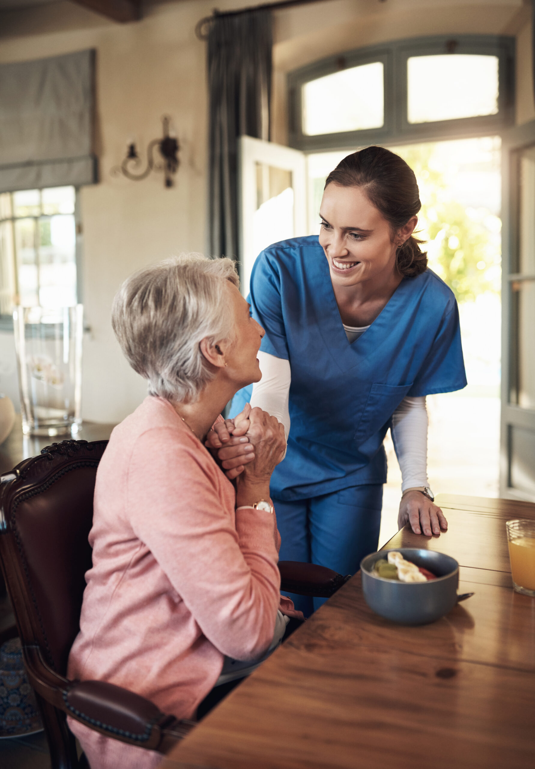Shot of a young nurse checking up on a senior woman during breakfast at a nursing home.